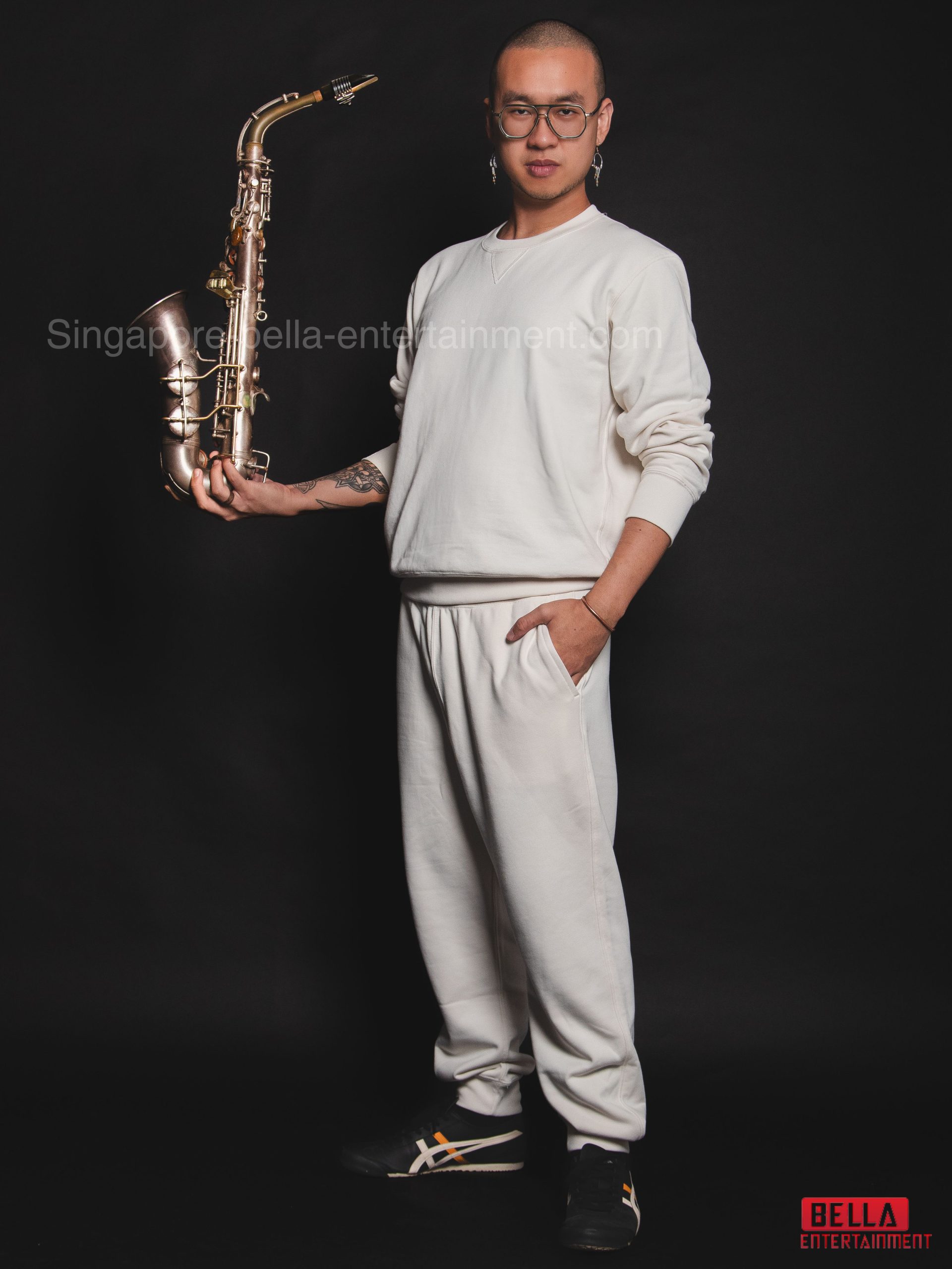Man wearing a white sweatshirt and pants, holding a saxophone in his hands, Saxophonist
