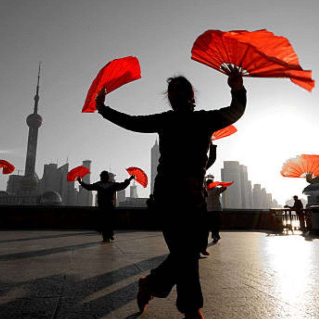 Group of people walking down a street in Shanghai, China, holding red Chinese fans in their hands, Chinese Entertainment Singapore for Hire