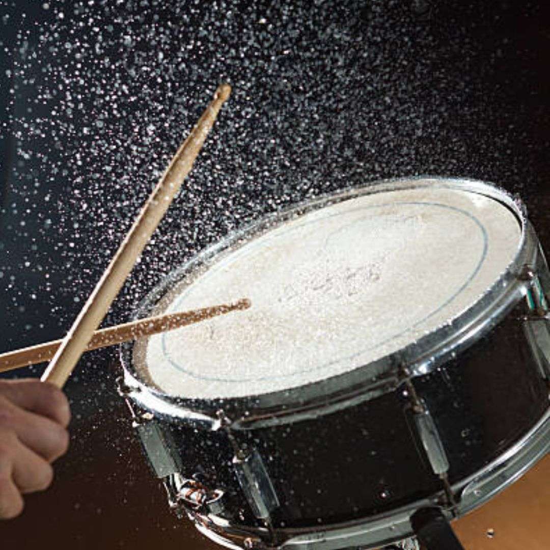 Person playing a snare drum with two drumsticks, their hand firmly gripping the sticks as they play, LED Water Drummer for Hire