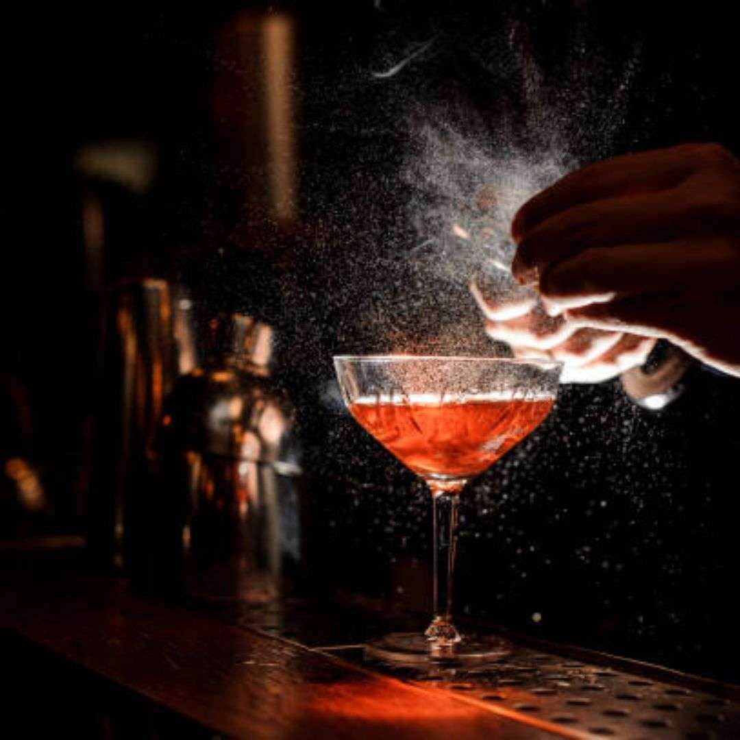 Bartender pouring a cocktail into a martini glass on a bar, Hire Gala Dinner Performance in Singapore