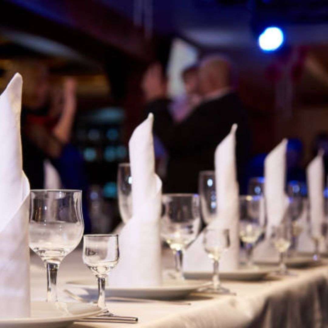 Long table set for a formal dinner with glasses, plates, spoons, and napkins neatly arranged on top, Hire Corporate D&D in Singapore